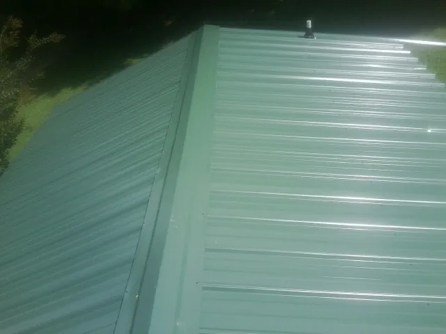 New green metal panels meeting at the ridge of a roof in Spring Grove