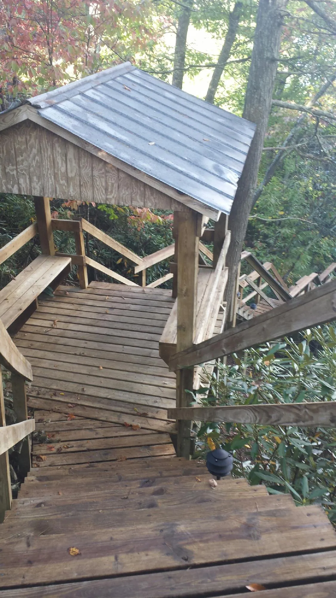Metal roofed shelter over wooden steps on a wooded walkway — Skylight Repair & Installation work by our crew in Spring Grove