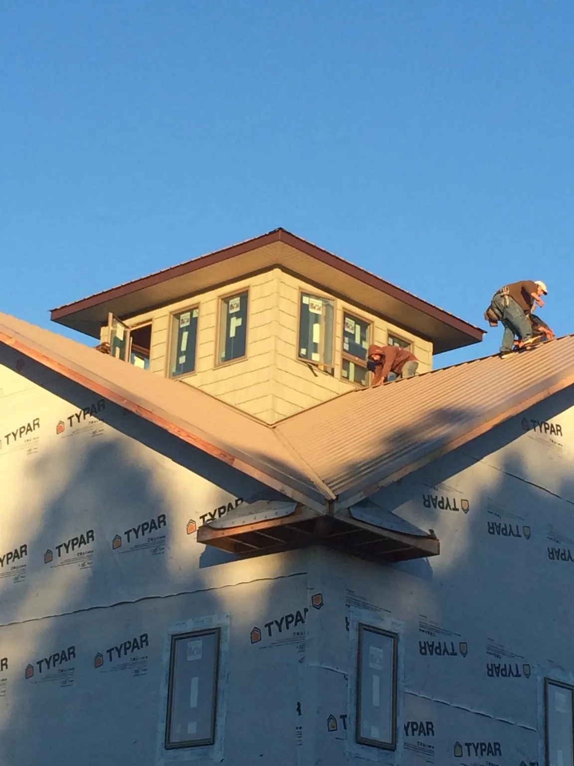 Roofers working around a rooftop cupola on a new metal roof at sunset — Roof Waterproofing in Spring Grove by Roofing Brothers